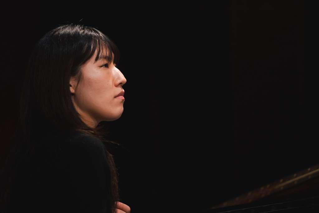 Yujin Han in profile with a black background