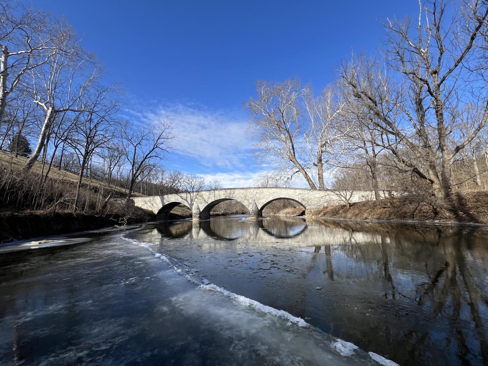 snow covered stone bridge with blue sky