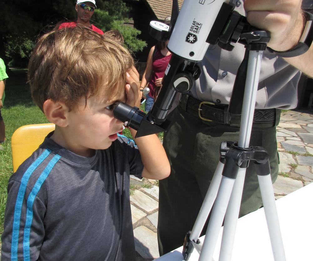 A small boy looks through a telescope.