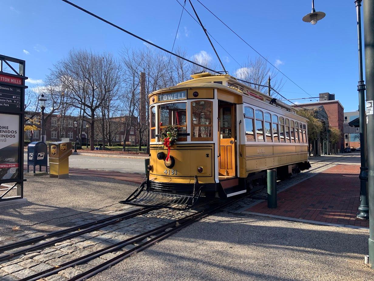 A yellow trolley with a holiday wreath attached to the front