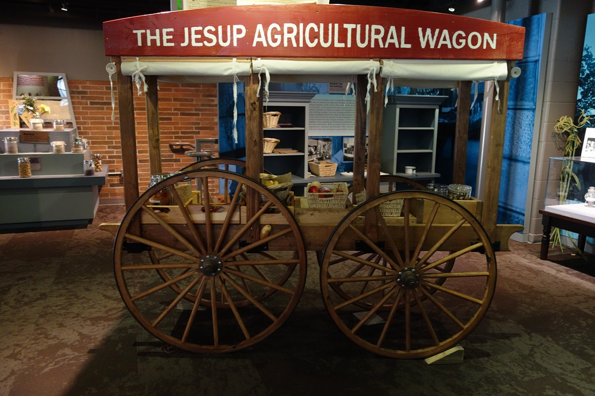 Wood wagon with large wheels and canvas roll up sides.