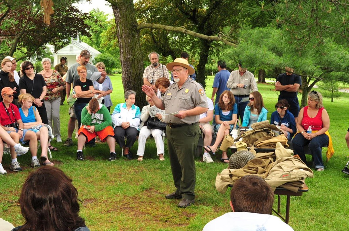 A park ranger talks to a group of people seated around him.