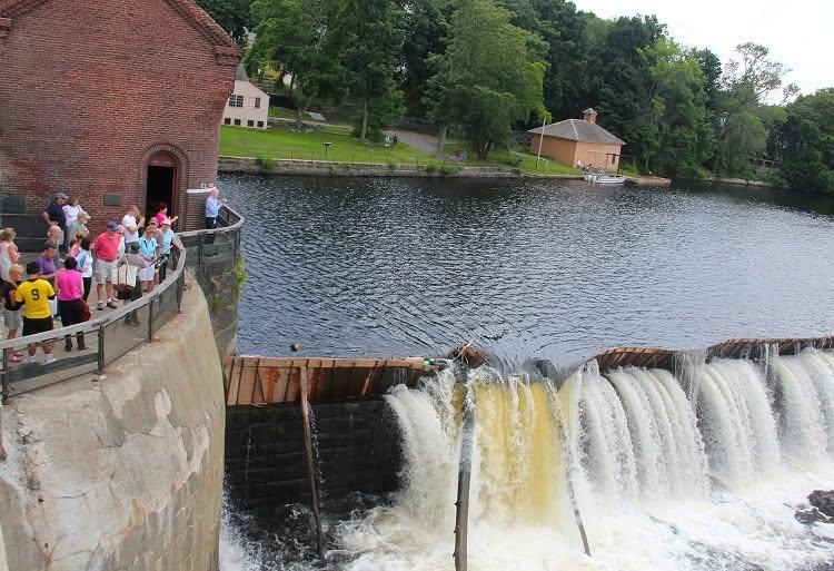 Photograph of a ranger talking to a group of people at the edge of a large dam.