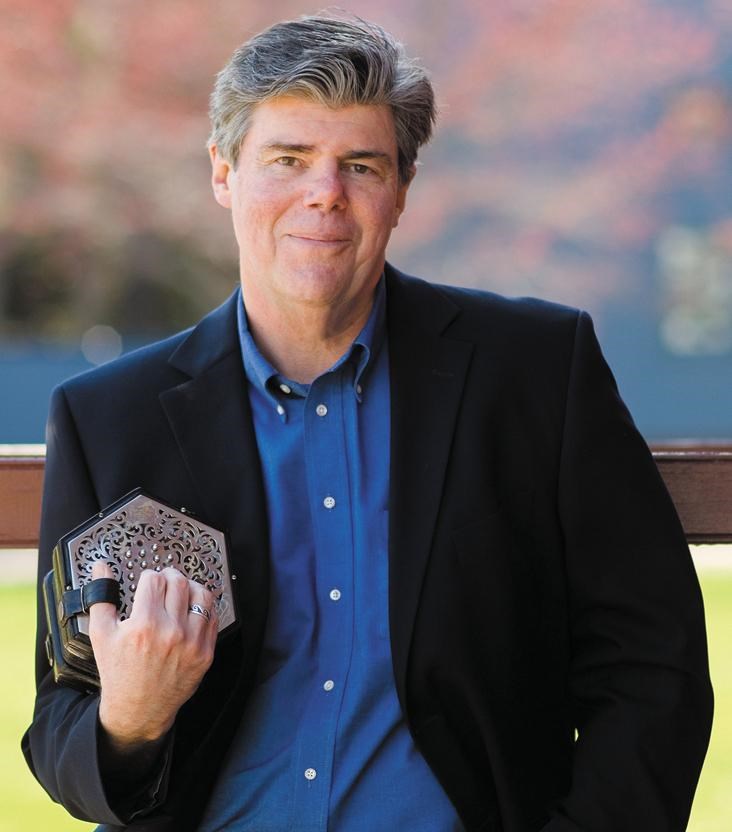 Jeff Warner posing with a concertina in his right hand.