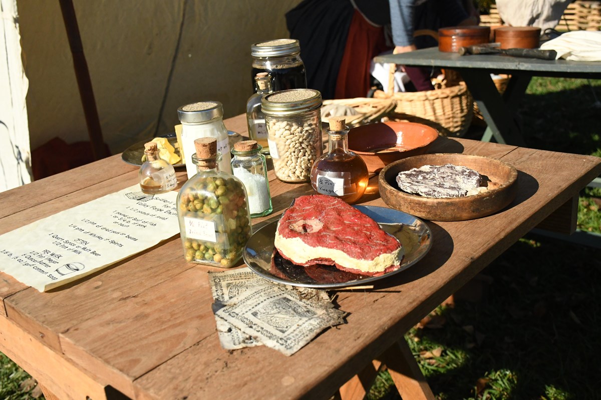 various foods are laid out on plates and in jars sitting on a table.