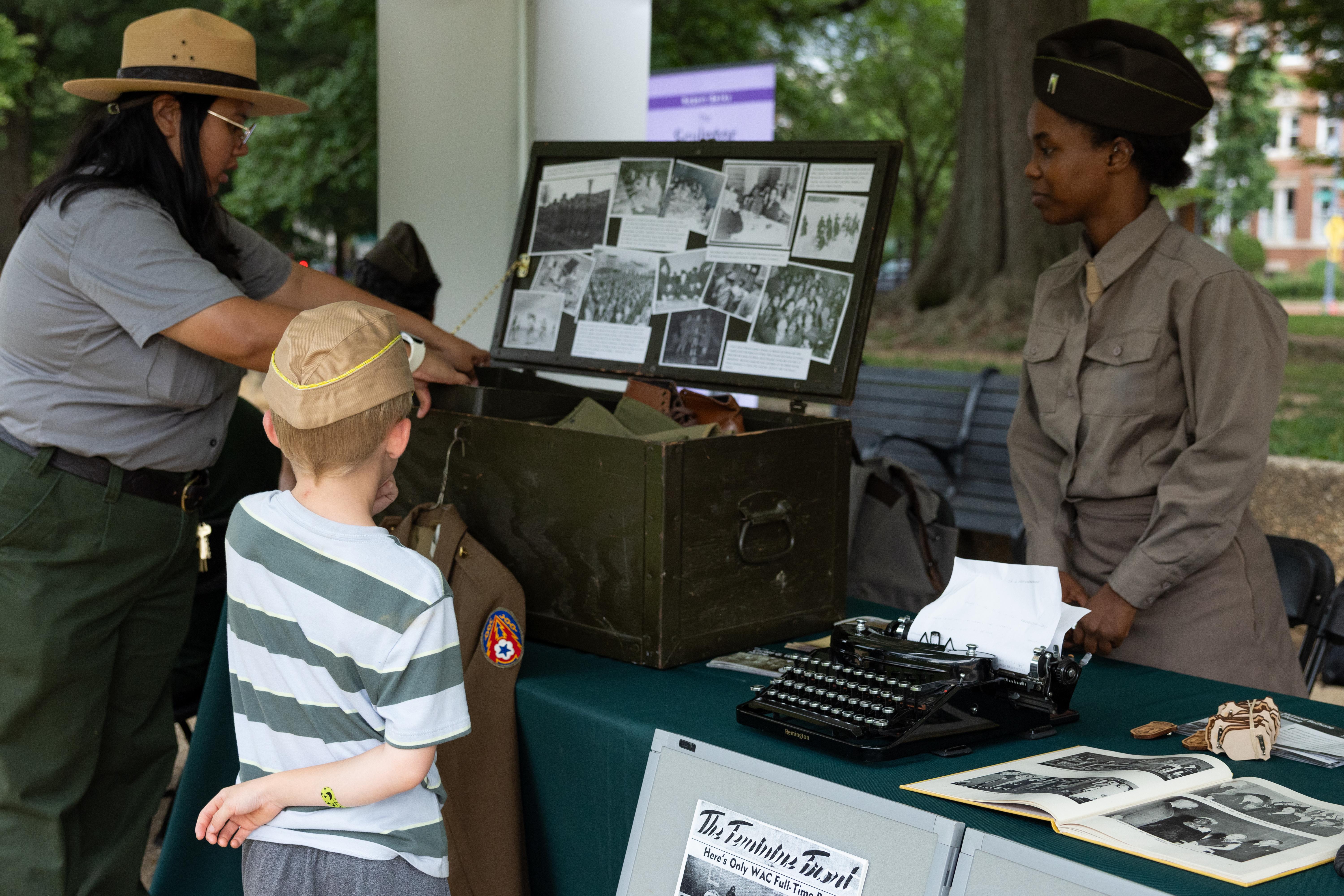 a young boy watches a park ranger and a young woman dressed as a 6888 Women's Army Corps soldier.
