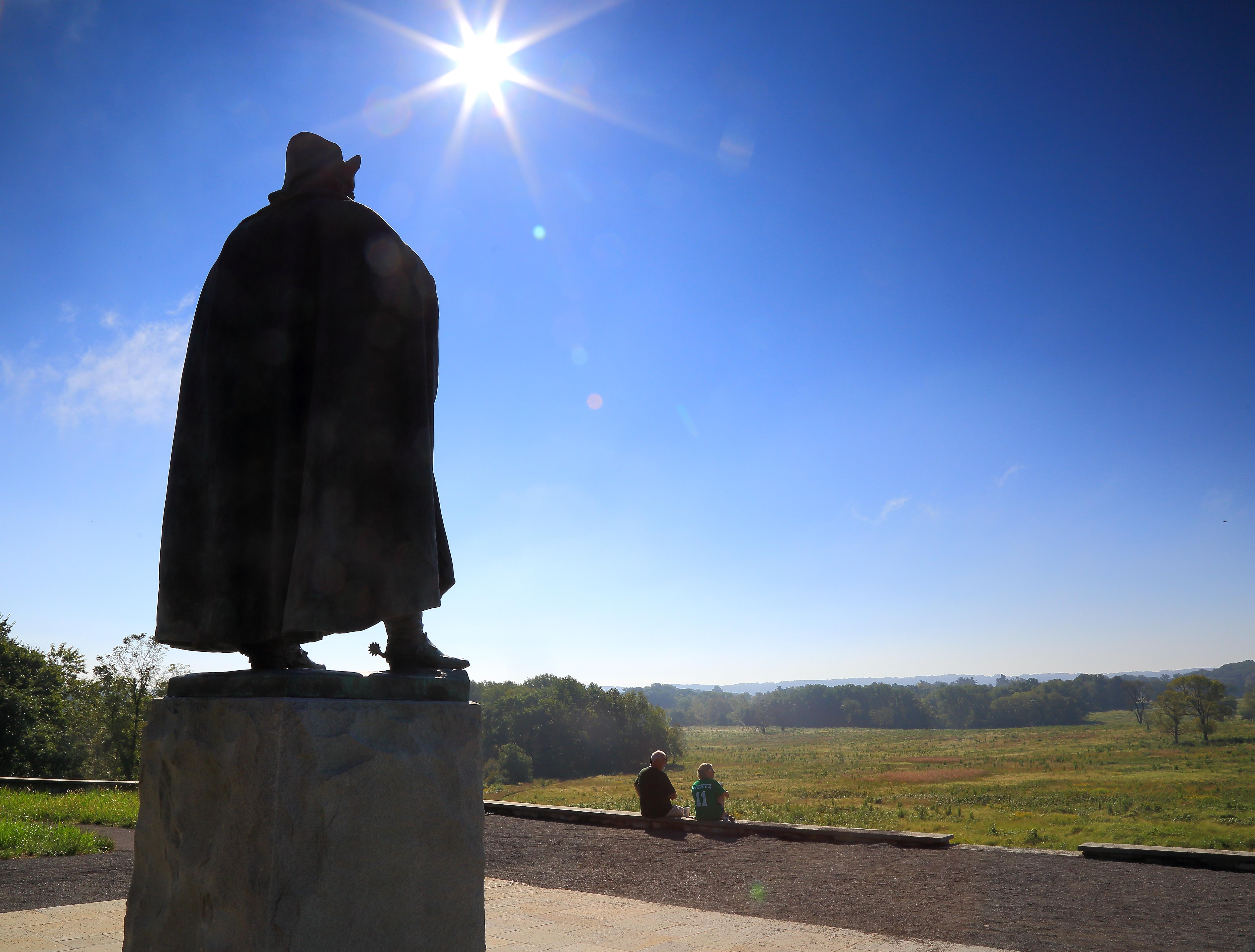 Two people sit looking over the meadows.