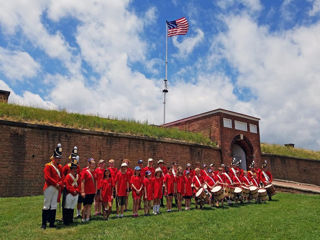 campers lined up in front of star fort with flag flying above