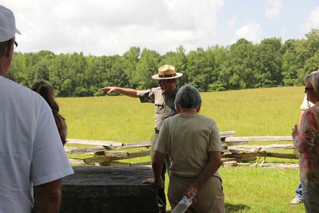 Ranger in green and gray uniform and flat hat pointing into the distance.