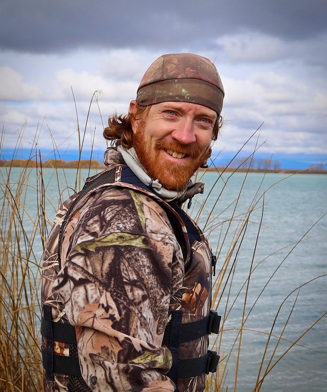 Smiling man dressed in camouflage.