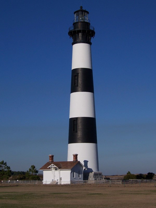 Black and white horizontally striped lighthouse on clear day with blue skies.