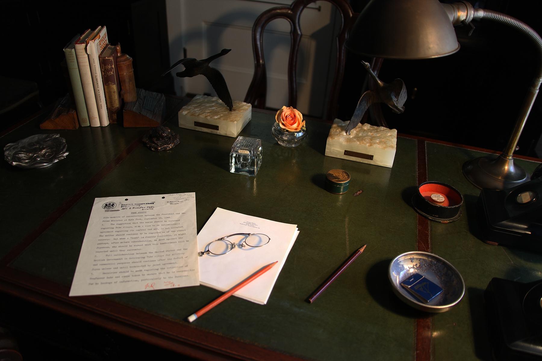 The top of a wooden desk covered in mementos from FDR's presidential years.
