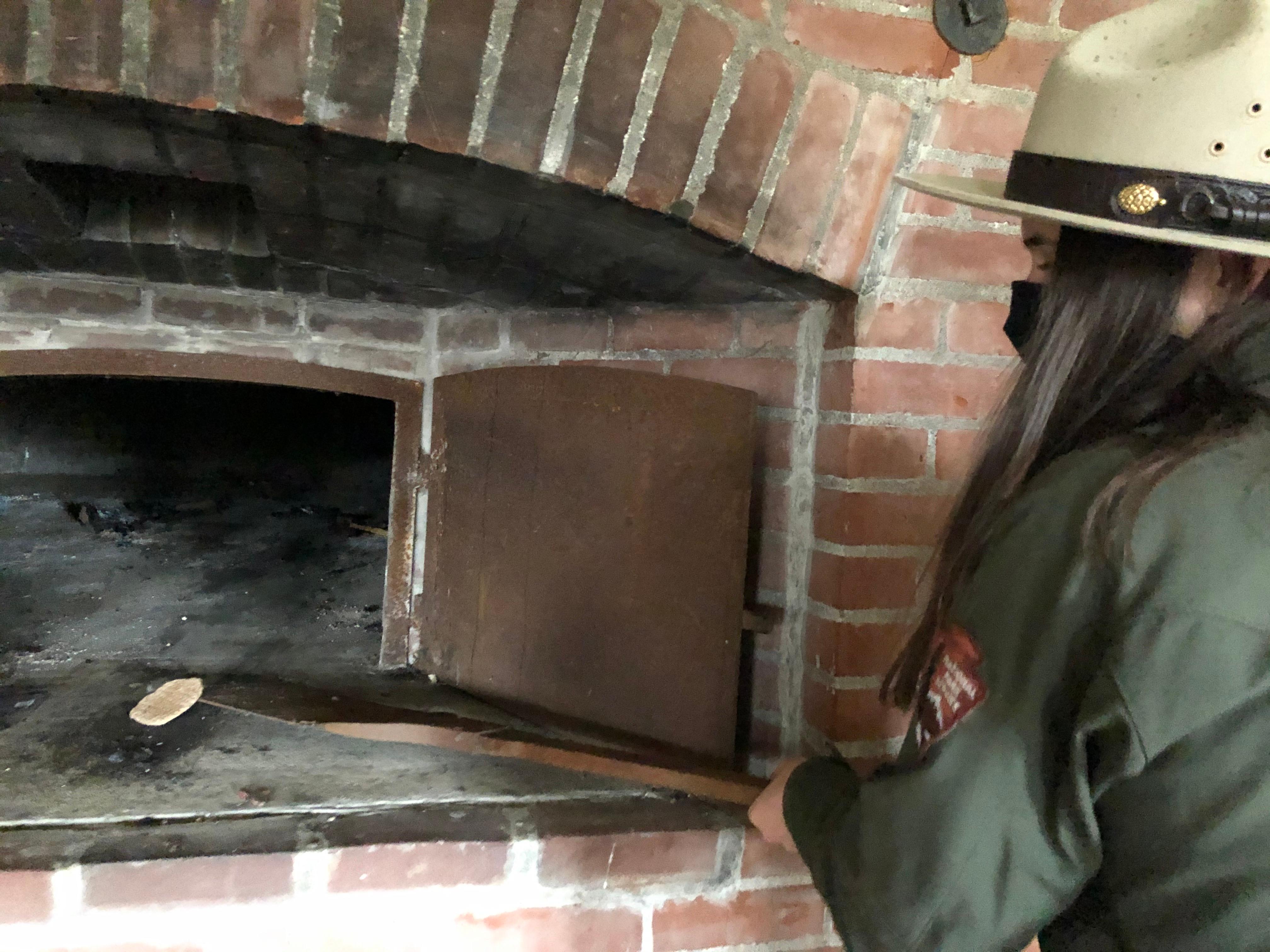 Park Ranger holding long piel with seabiscuit at the end of it. Brick oven in background.