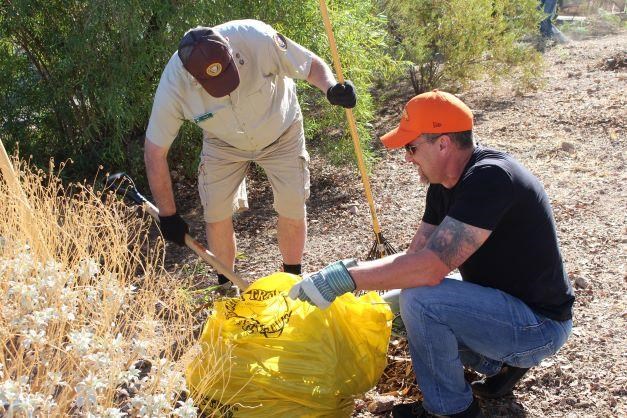 Two volunteers gathering debris in a park campground