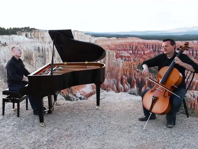 A man playing a piano and a man playing a cello along the rim of Bryce Canyon.