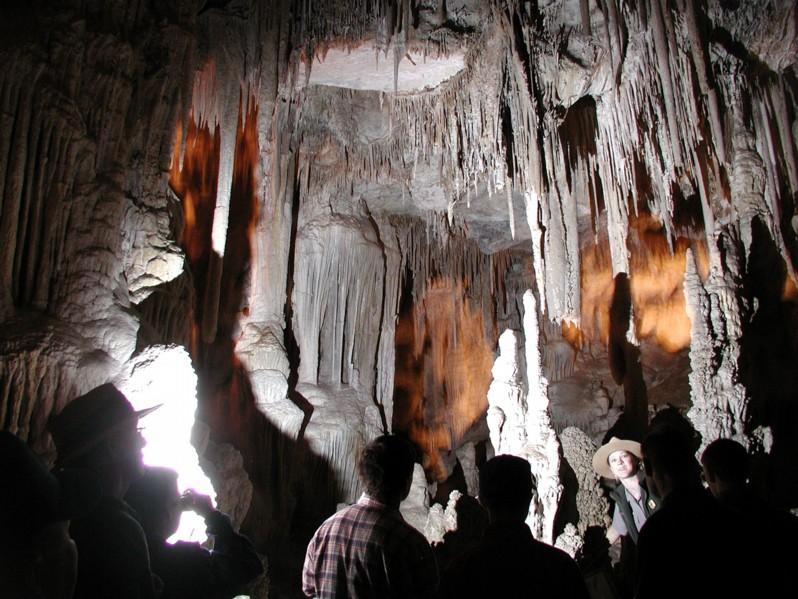 A group of visitors is silhouetted against backlit cave formations.