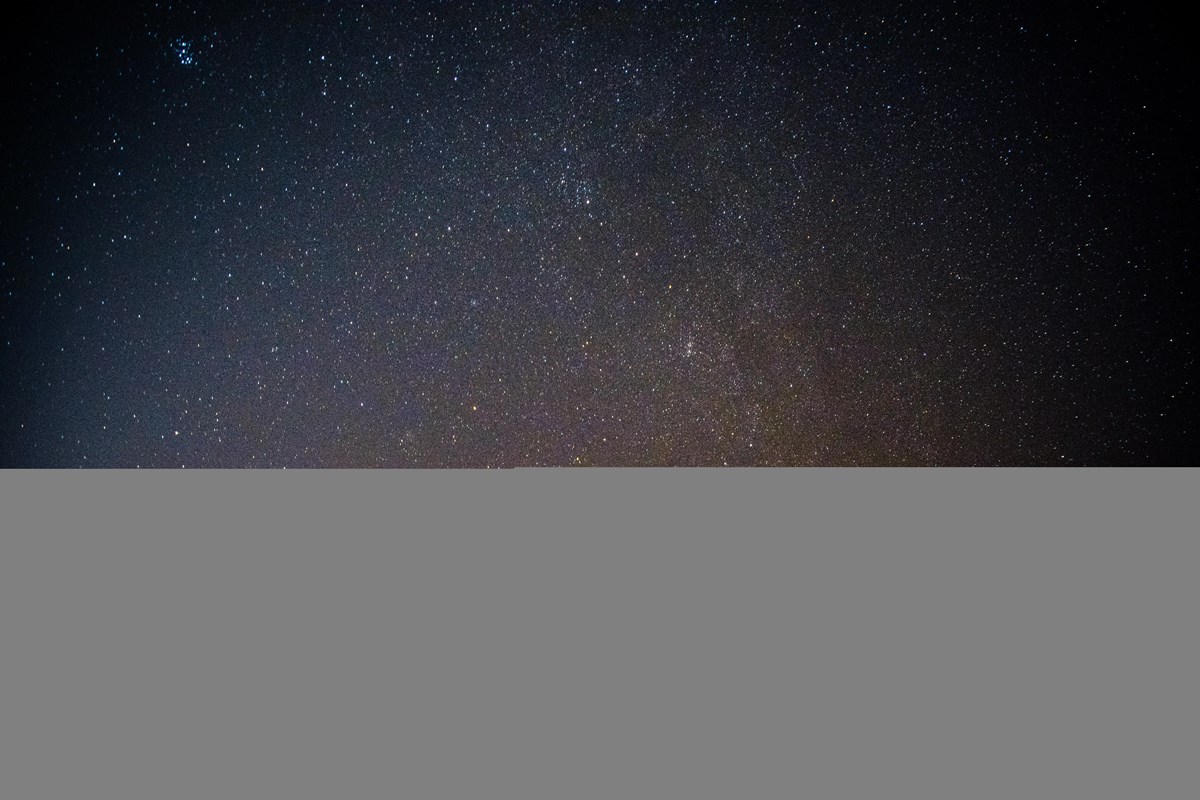 Tiny star points of light against a black and shades of blue night sky