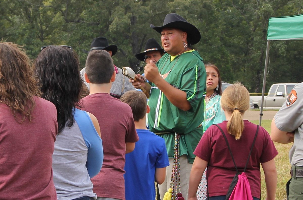 A Native American man talks to a group of chidren.