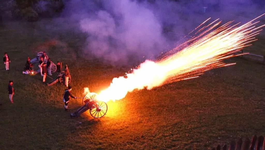 An 18th century cannon fires at night and sprays a massive flame out of the barrel
