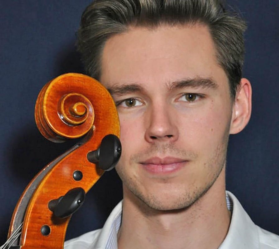 portrait of a young musician against a black background. The scroll of his cello touching his face.