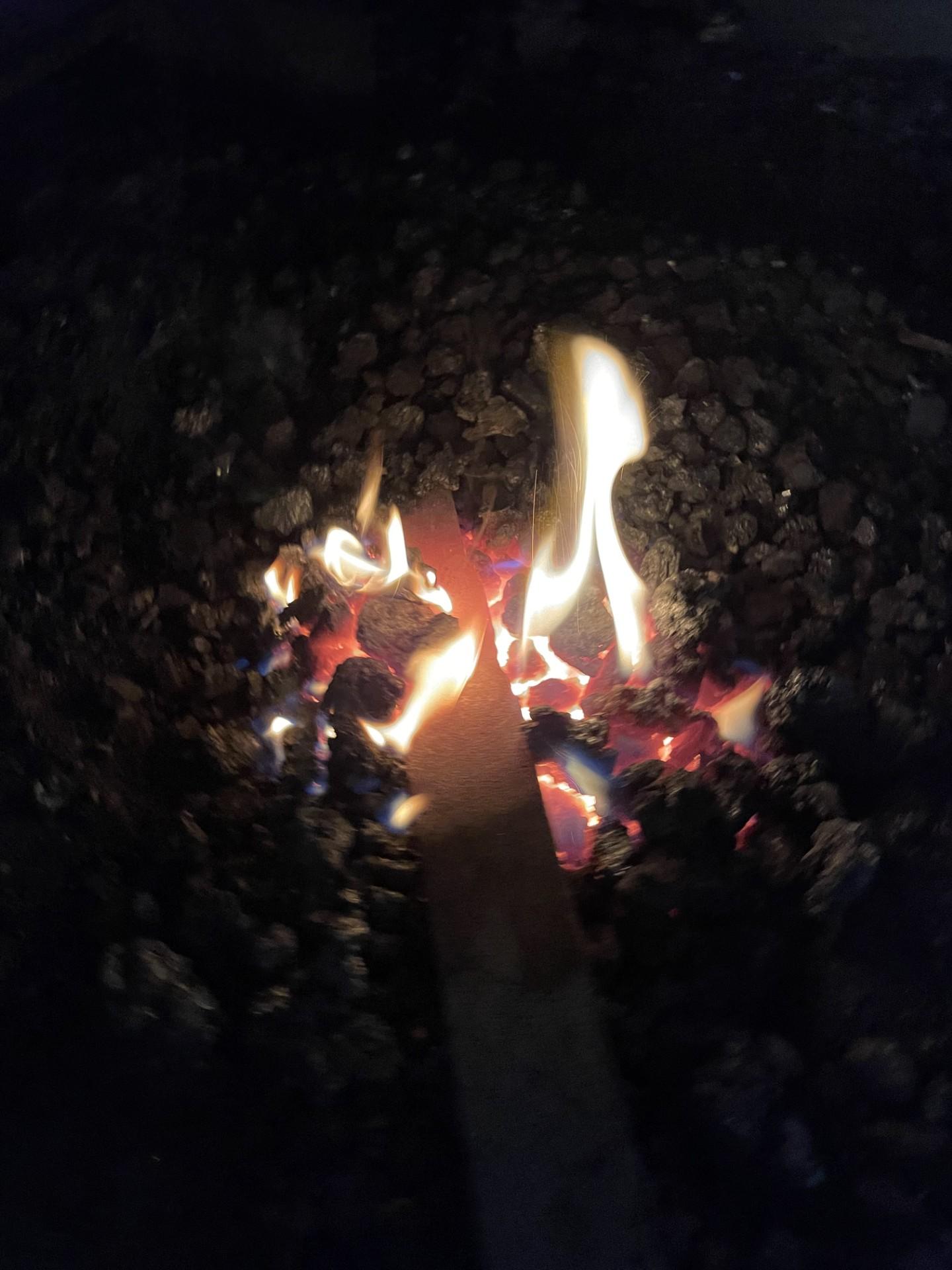 A piece of metal lays in the coals