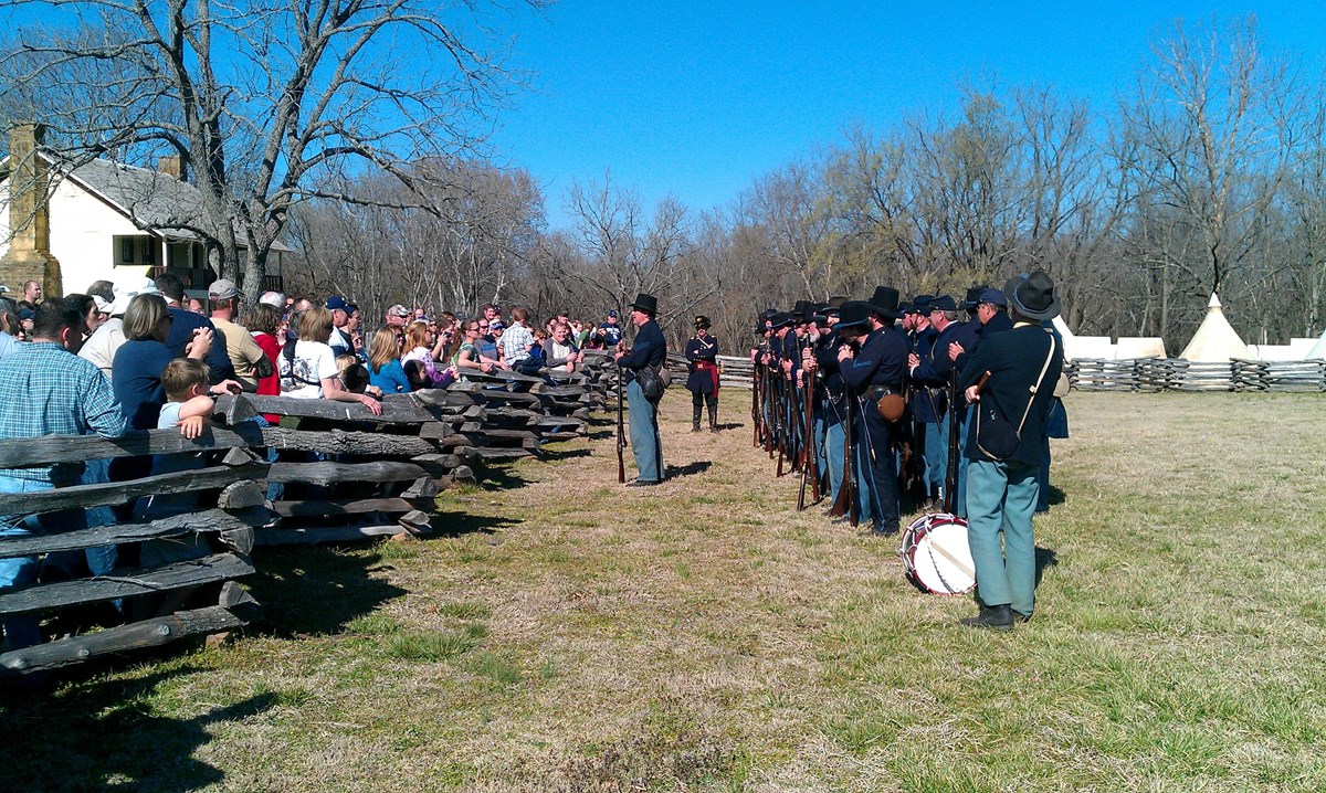 Photo of living history soldiers standing talking to visitors.