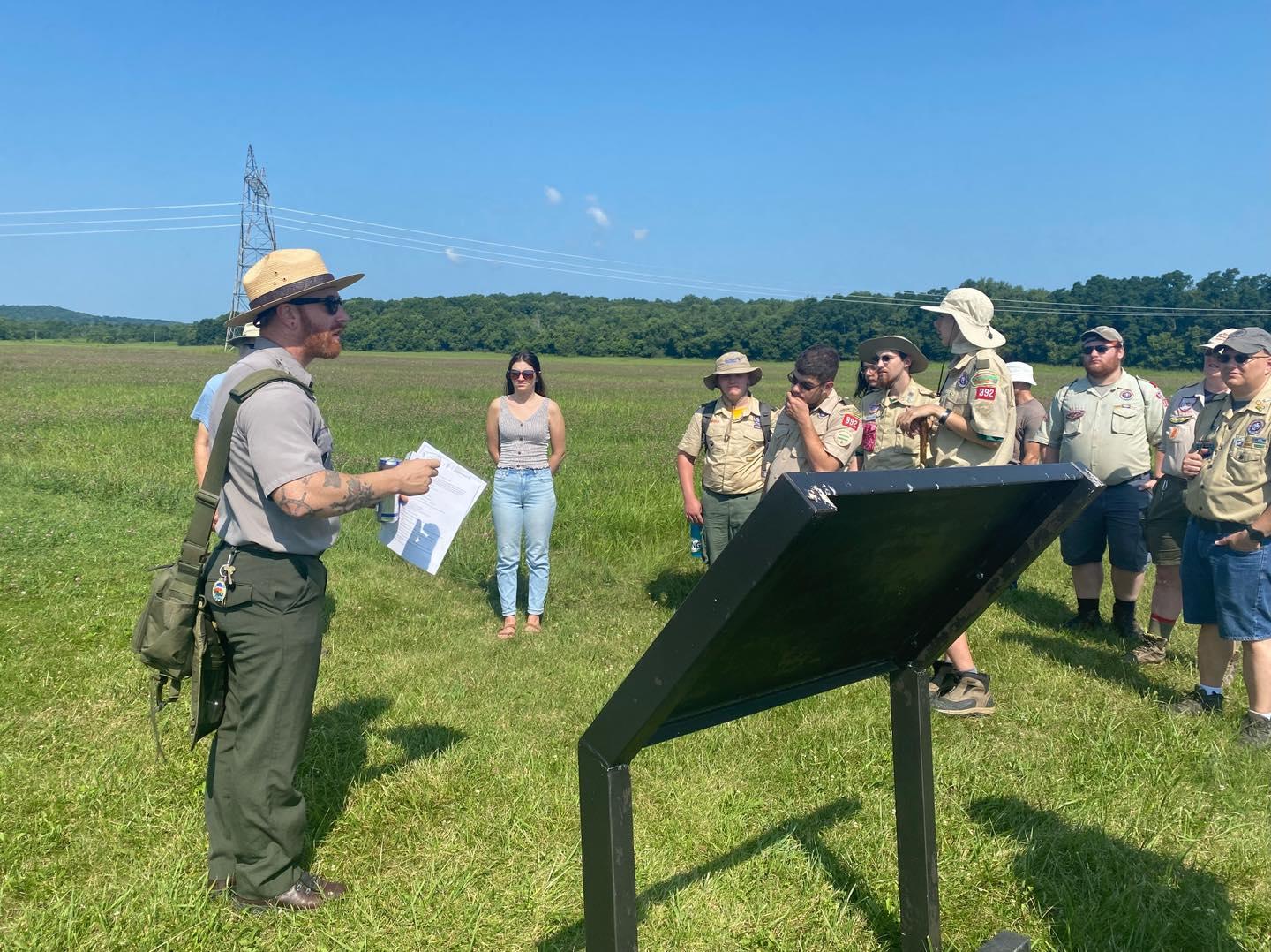 A park ranger guides a group through a large outdoor space.
