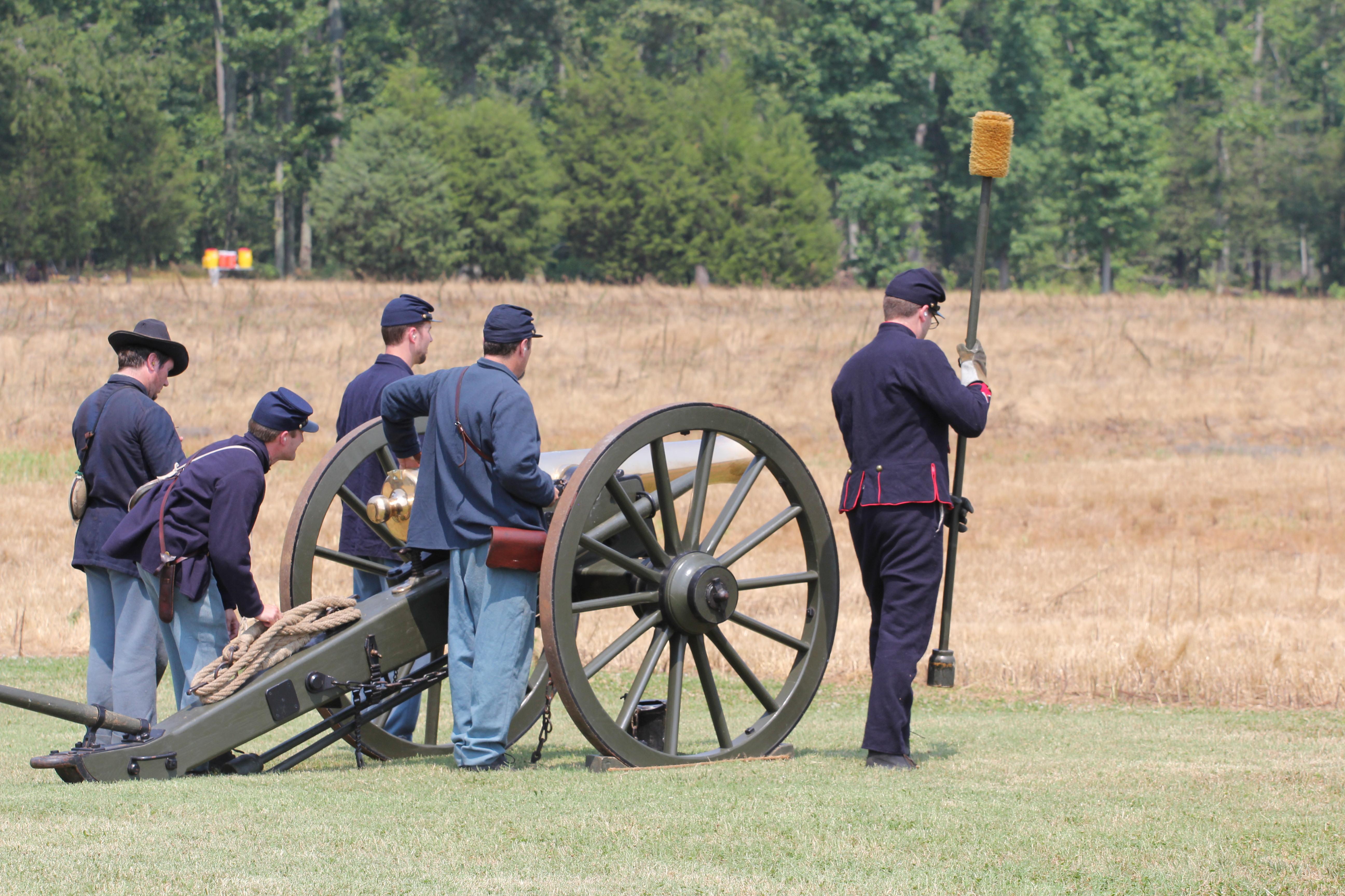 Five men in blue Civil War uniforms standing around a bronze cannon