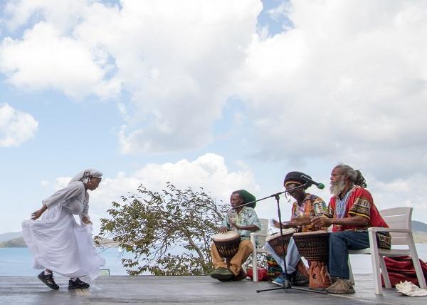 A woman in white dancing to tree drummers