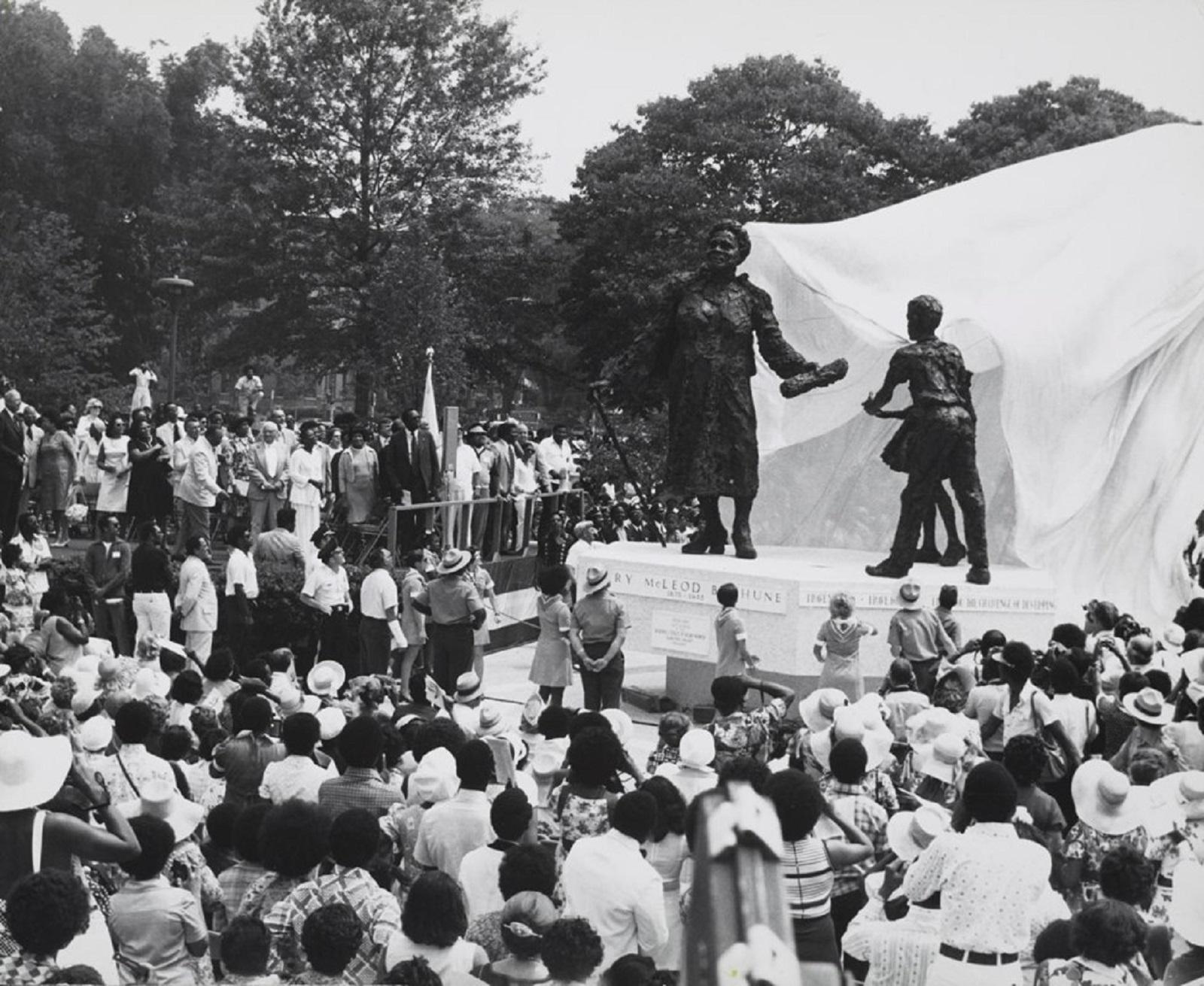 A crowd of people gathered outside in front of a large statue.