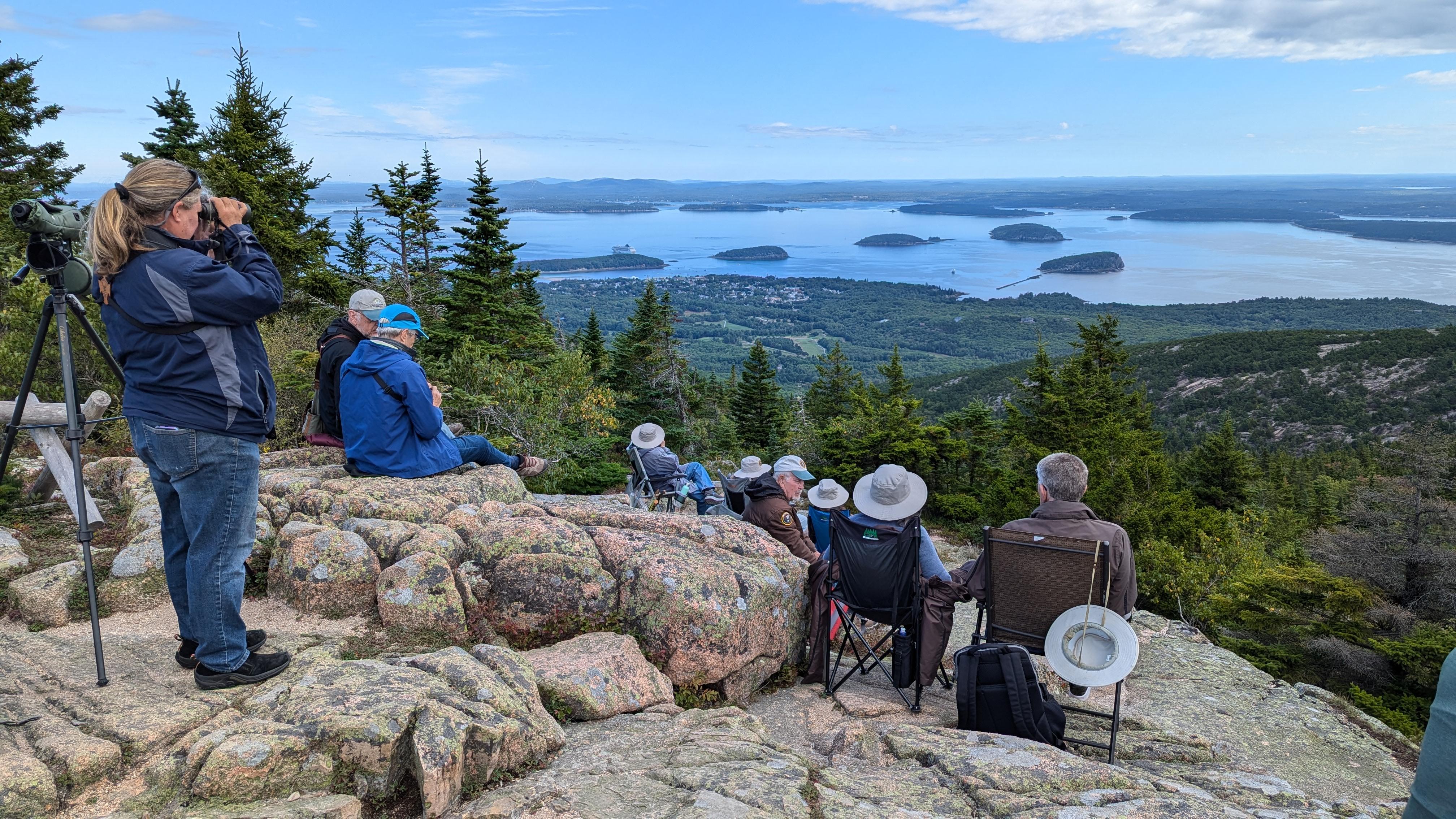 A group of staff and volunteers with binoculars looking over the water