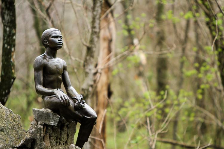 Bronze statue of young George Wahsington Carver holding a plant.