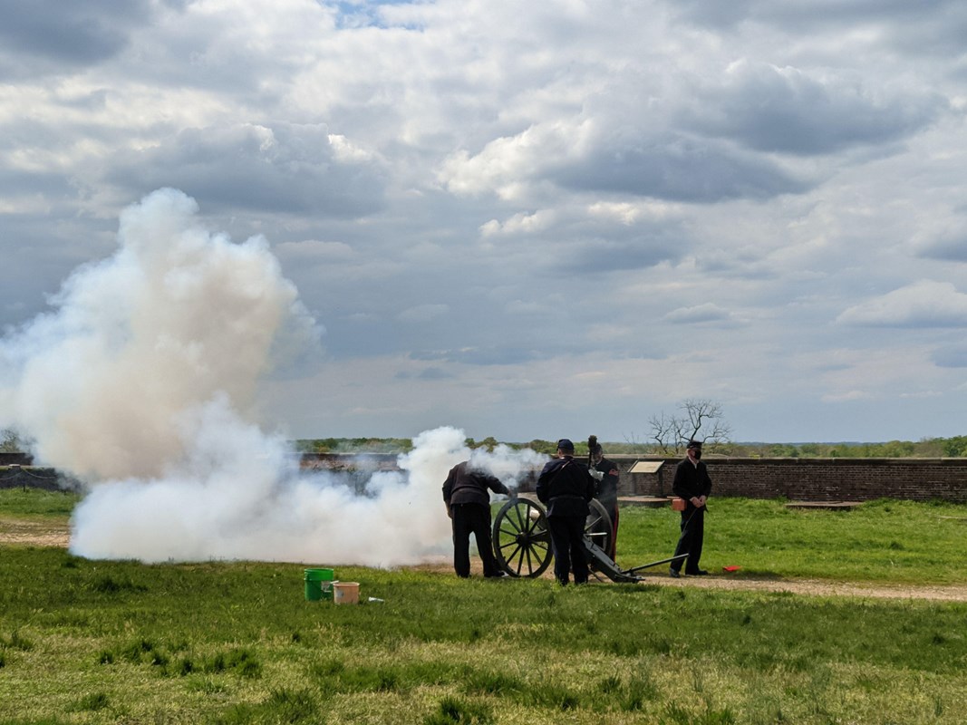 Smoke billows from a cannon by four uniformed men