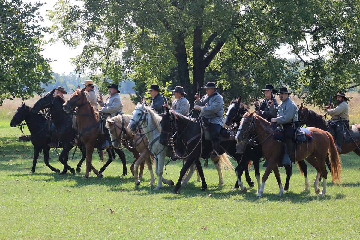 Confederate cavalrymen ride in a line.
