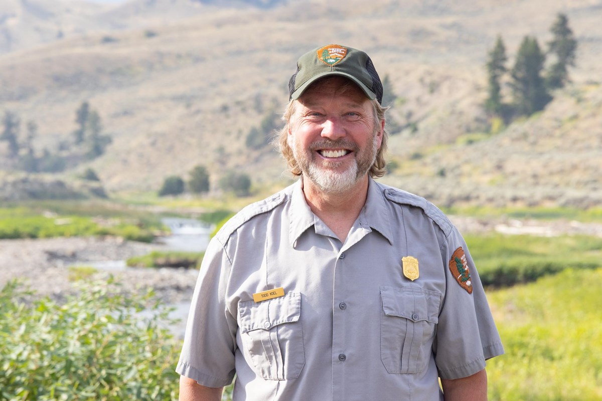 a man wearing a park ranger uniform and smiling at the camera