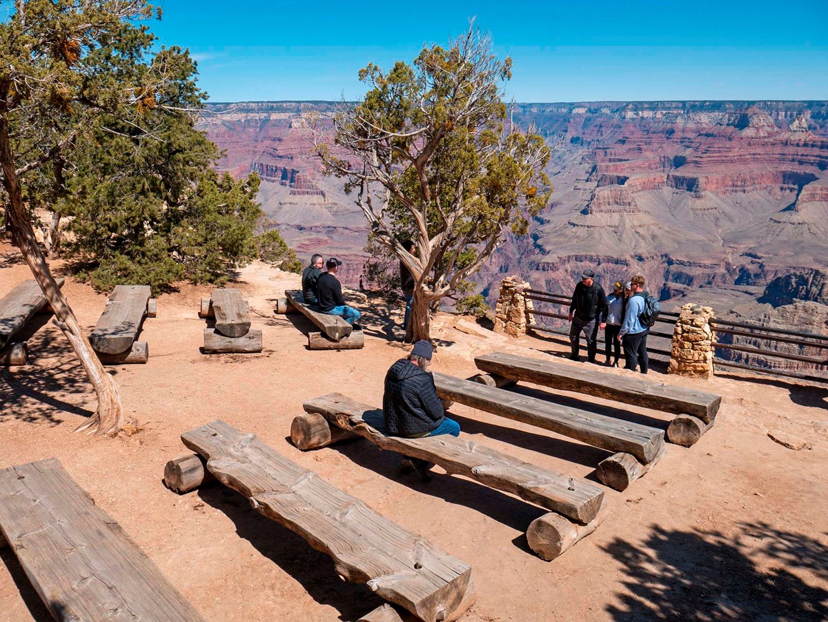 2 rows of split-log benches create an outdoor amphitheater at a scenic overlook with metal railings