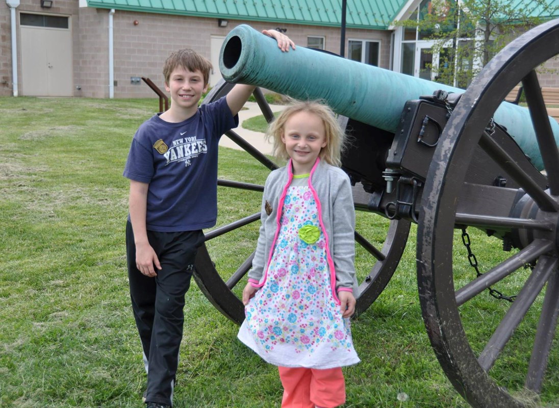 Two Junior Rangers standing beside a cannon