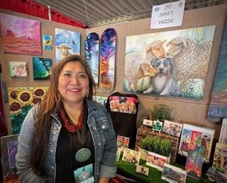 Diné artist Janet Yazzie sands in front of some of her paintings.