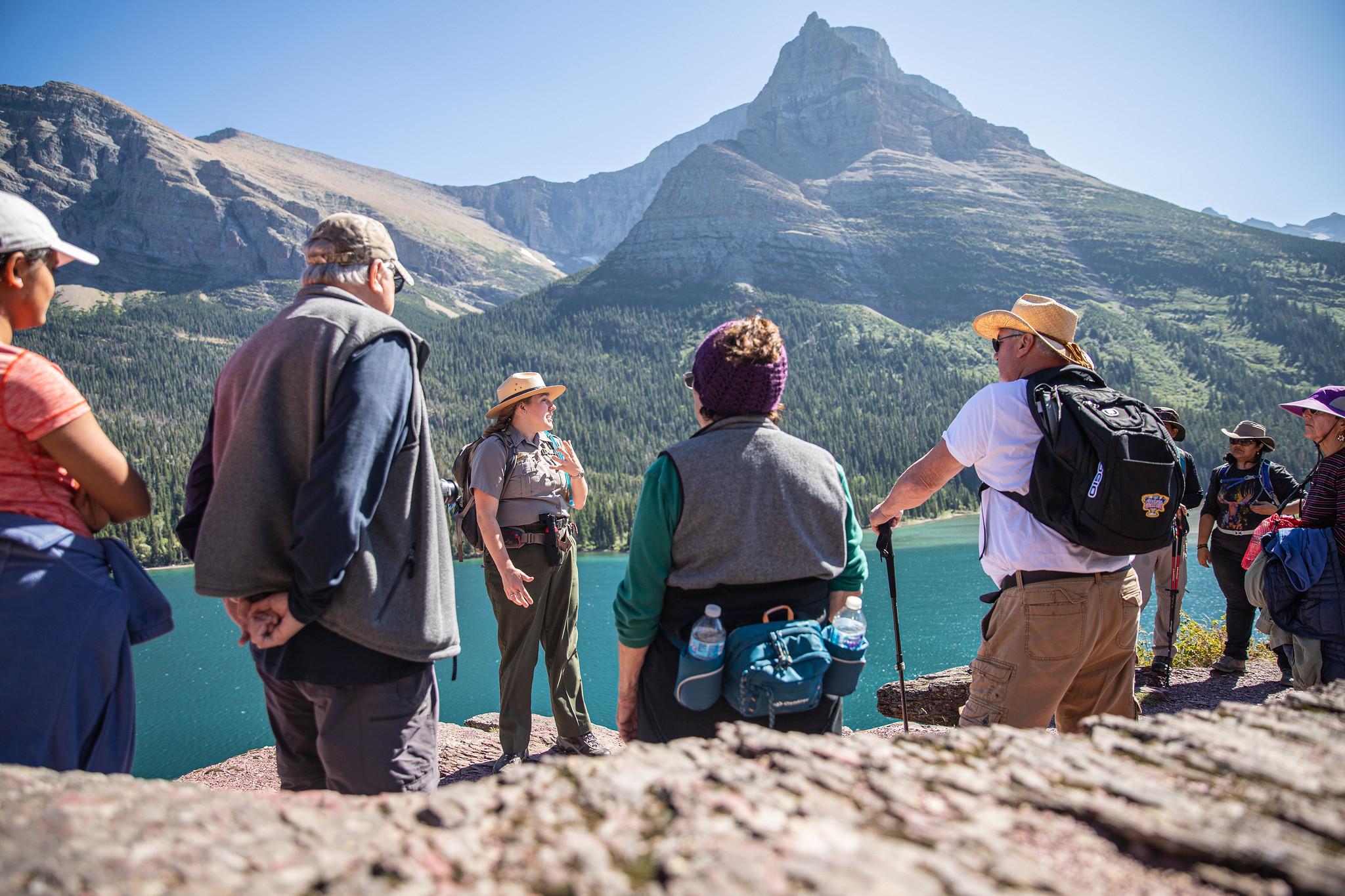 Ranger talking to a group with view of a lake and mountains