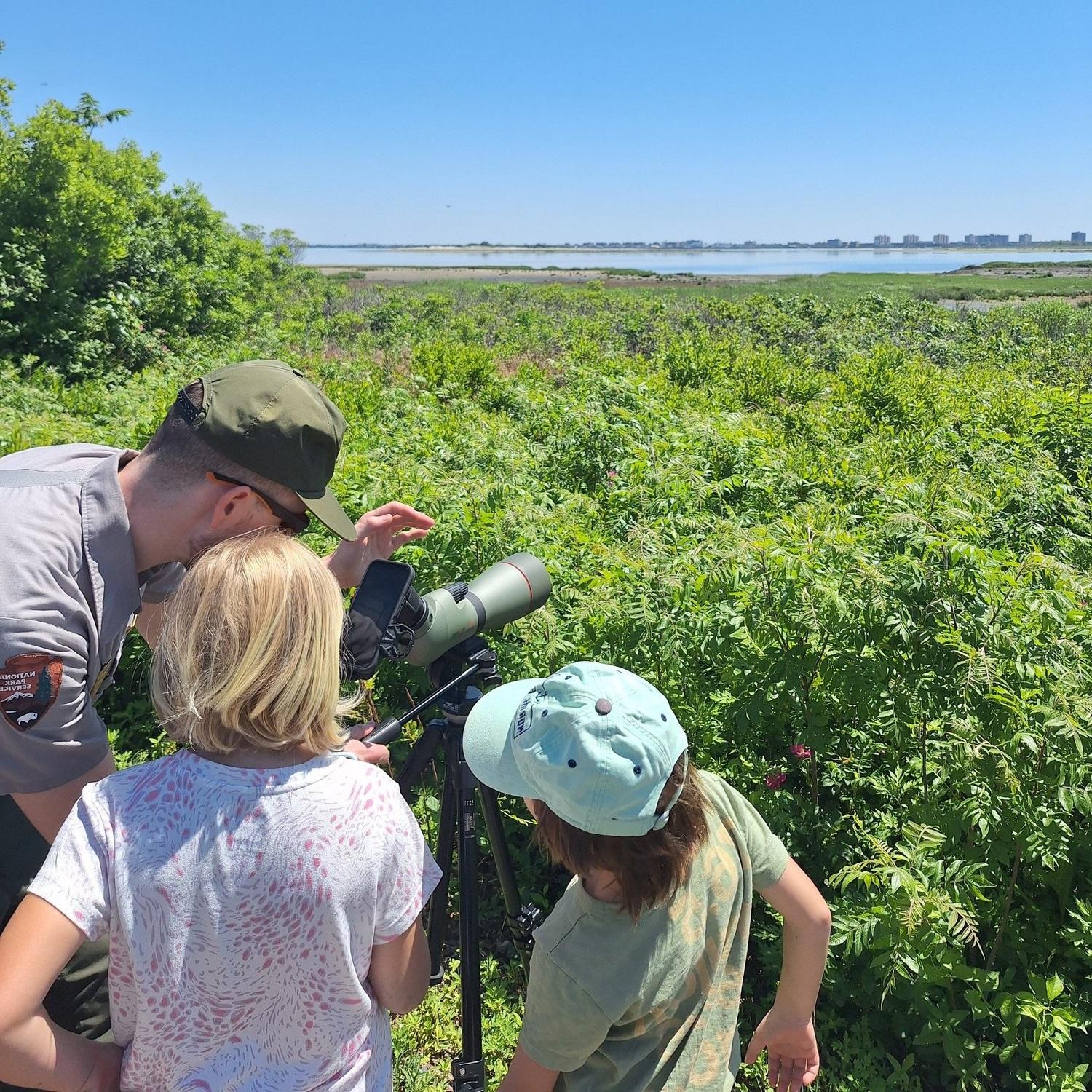 Park ranger with two Junior Rangers and a birding scope
