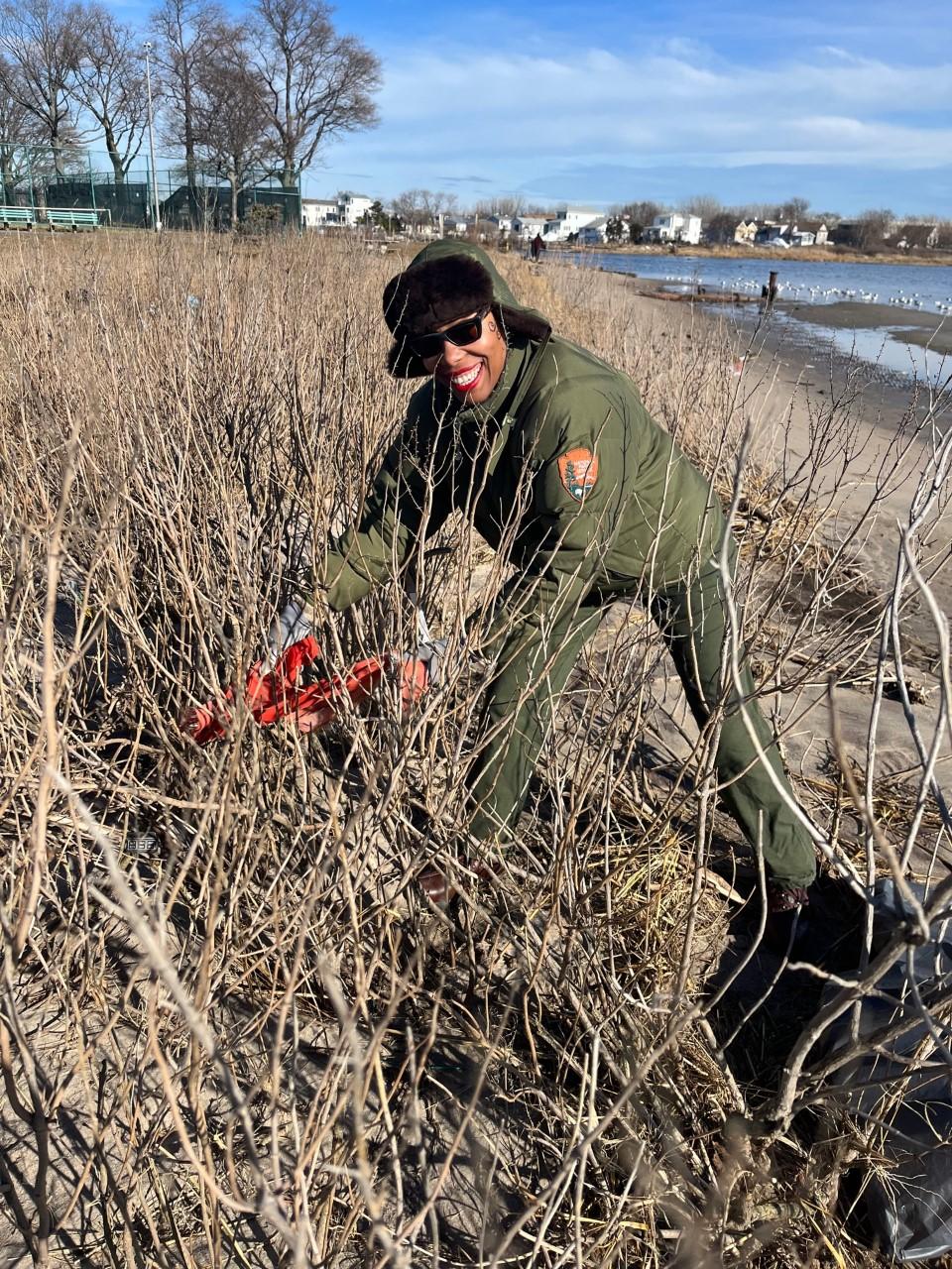 A park ranger cleaning up trash from a shoreline.