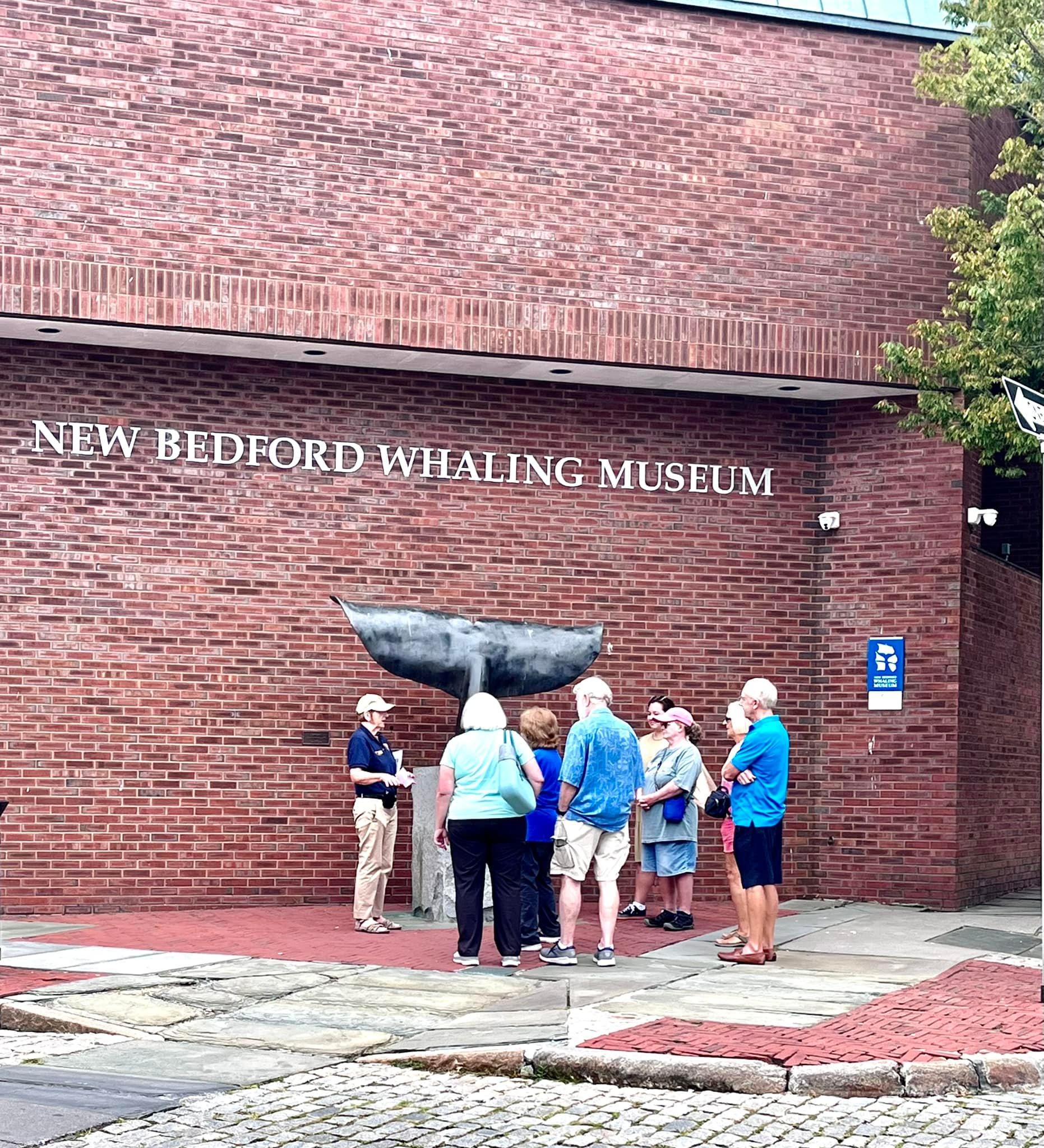 Park Volunteer with park visitors by a whale's tail