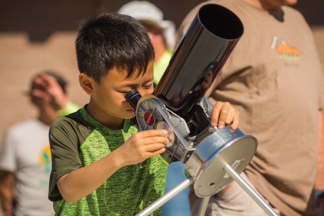 A child looks through a solar scope