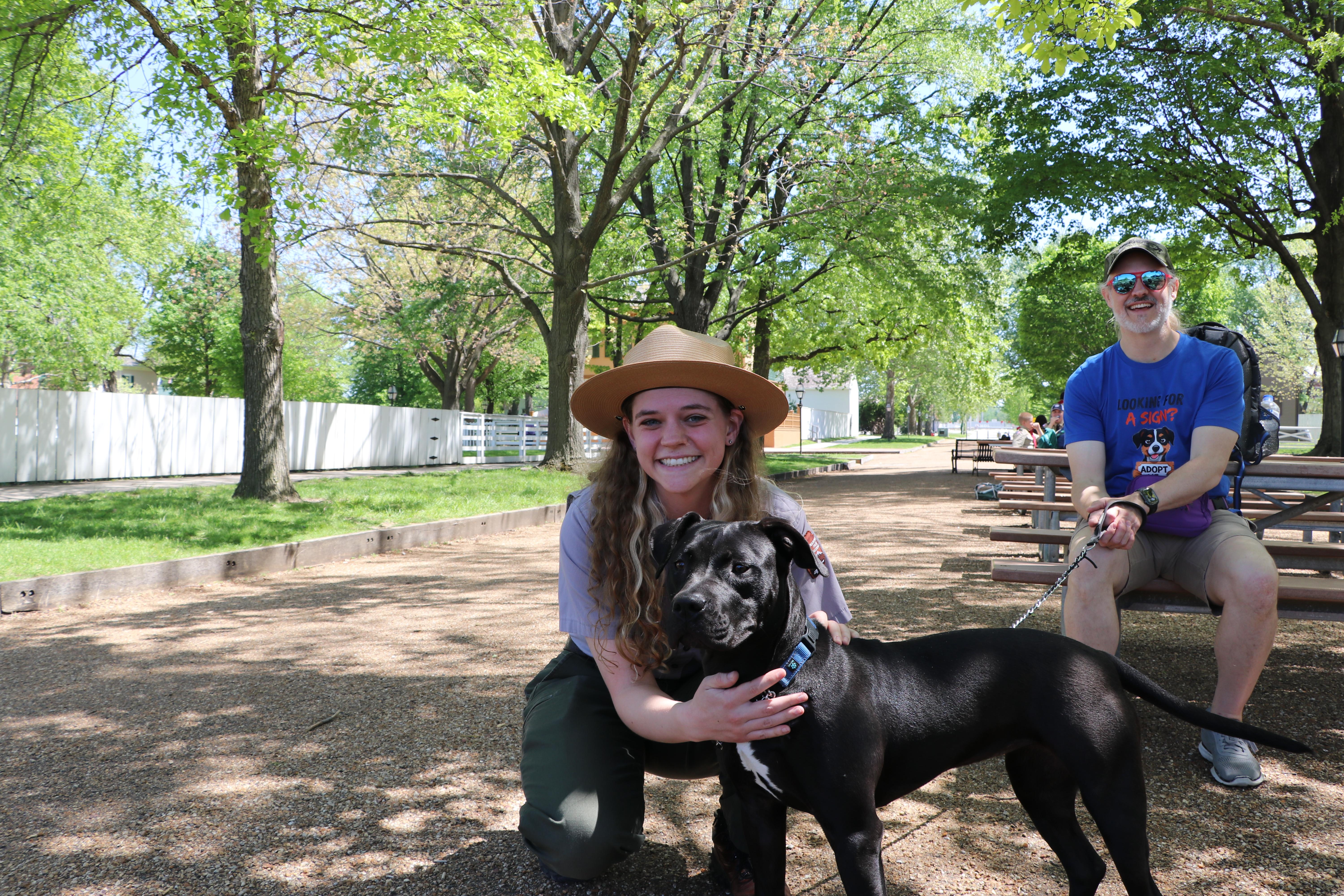 a park ranger and APL volunteer smile with a black dog