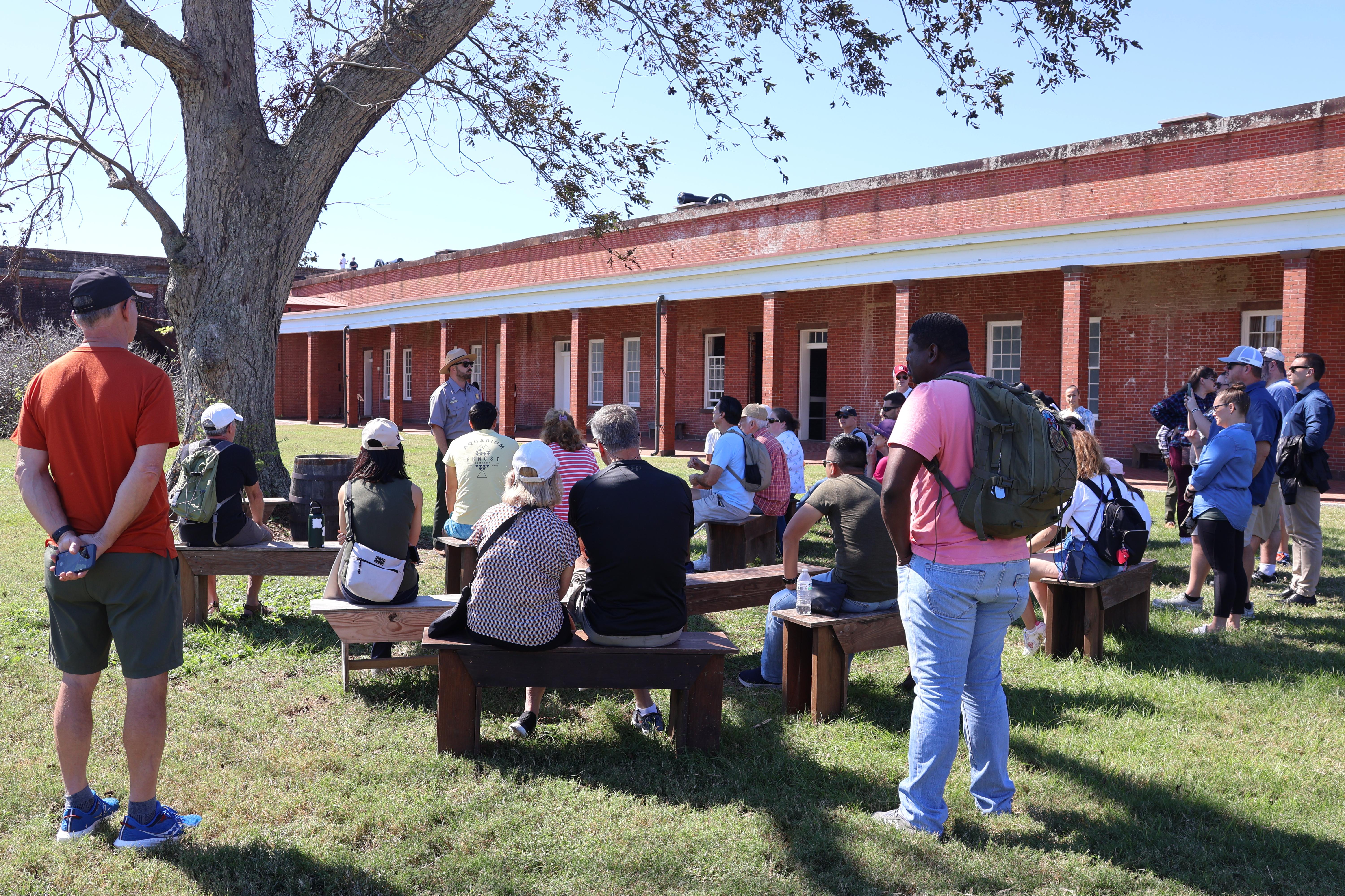 Park ranger giving a talk to several people under a tree.