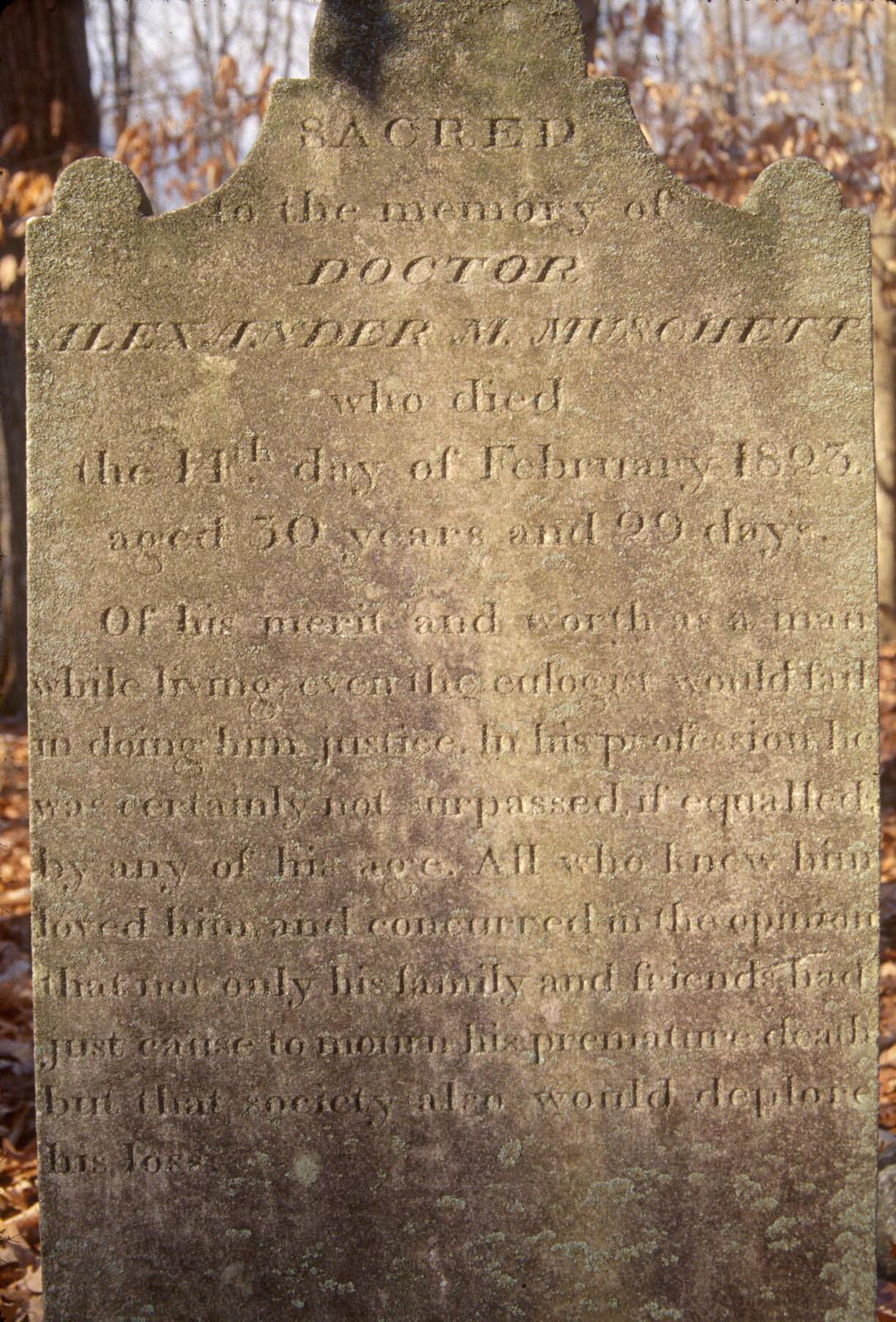 Engraved concrete headstone in a cemetery for Doctor Alexander M Muschett