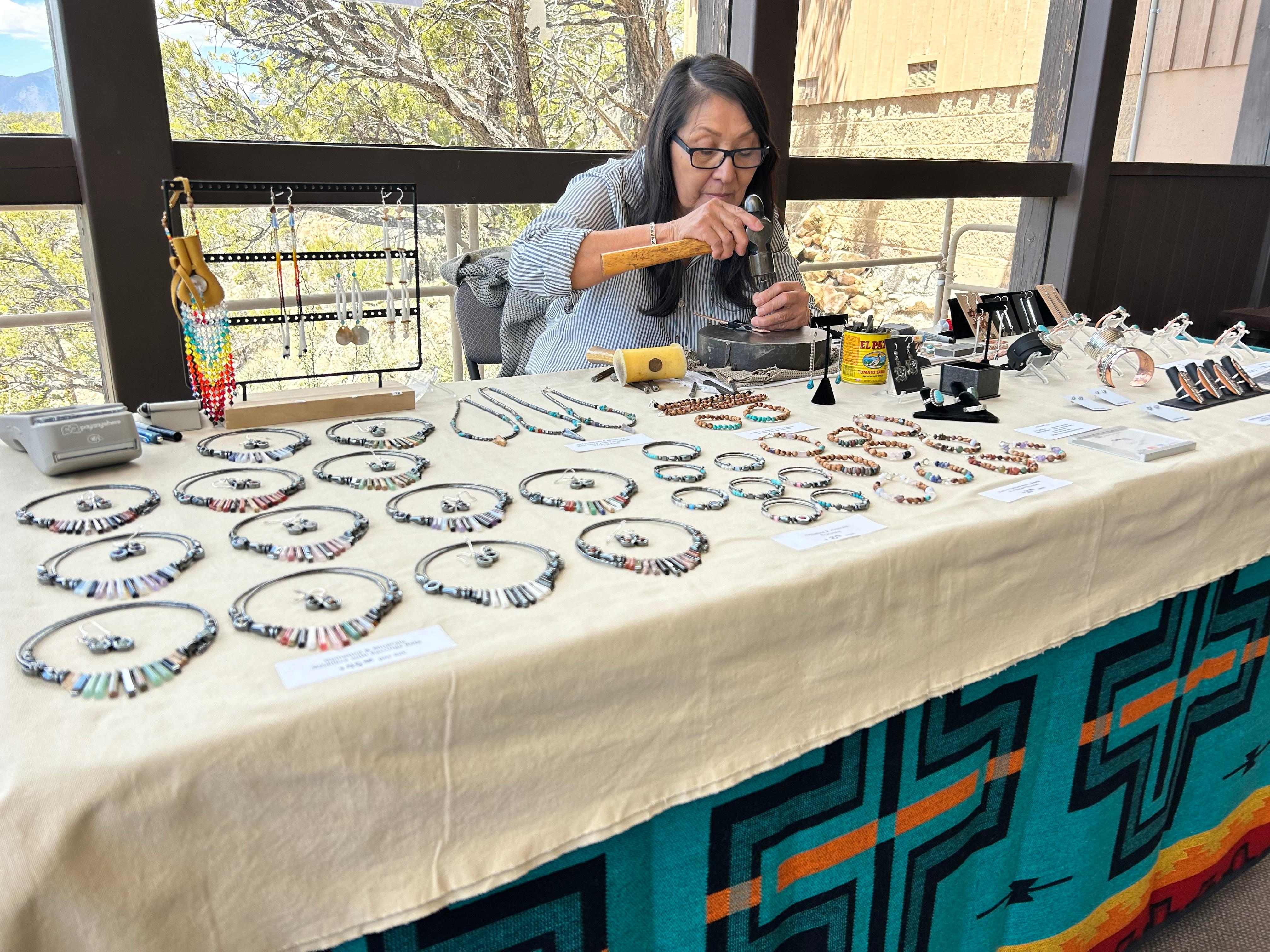 A dine Woman creates jewelry at the Visitor center
