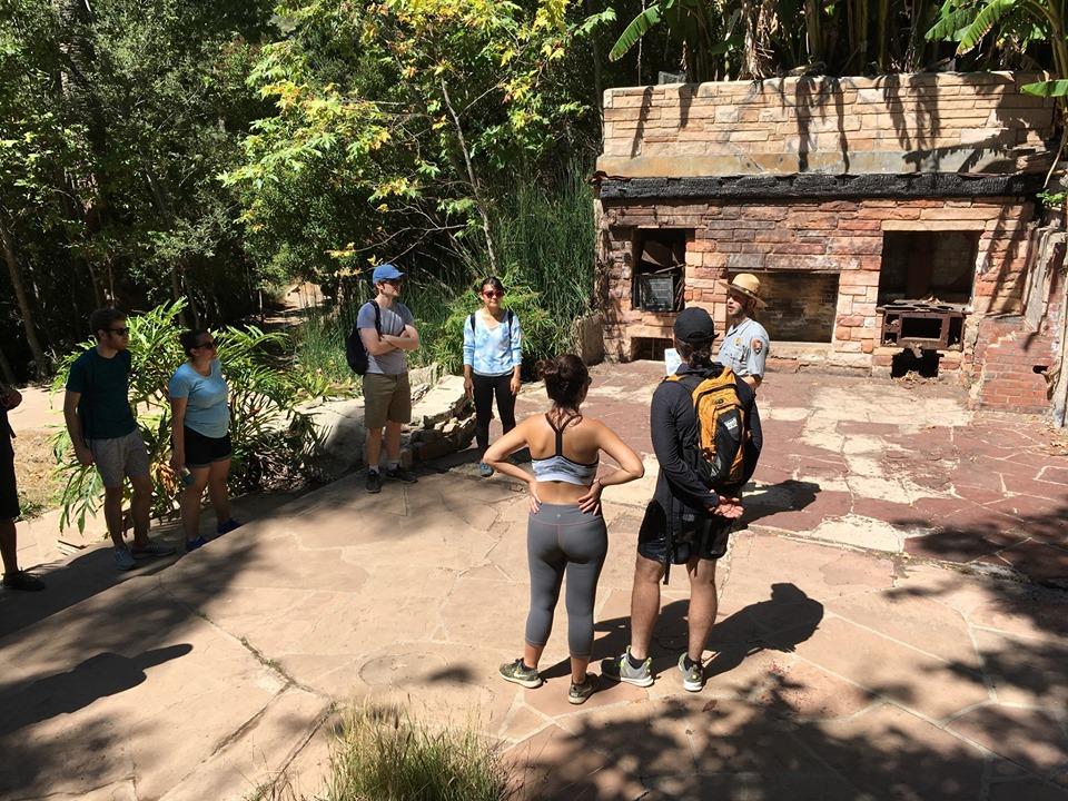 A park ranger talks to an audience of hikers in the ruins of the Roberts House