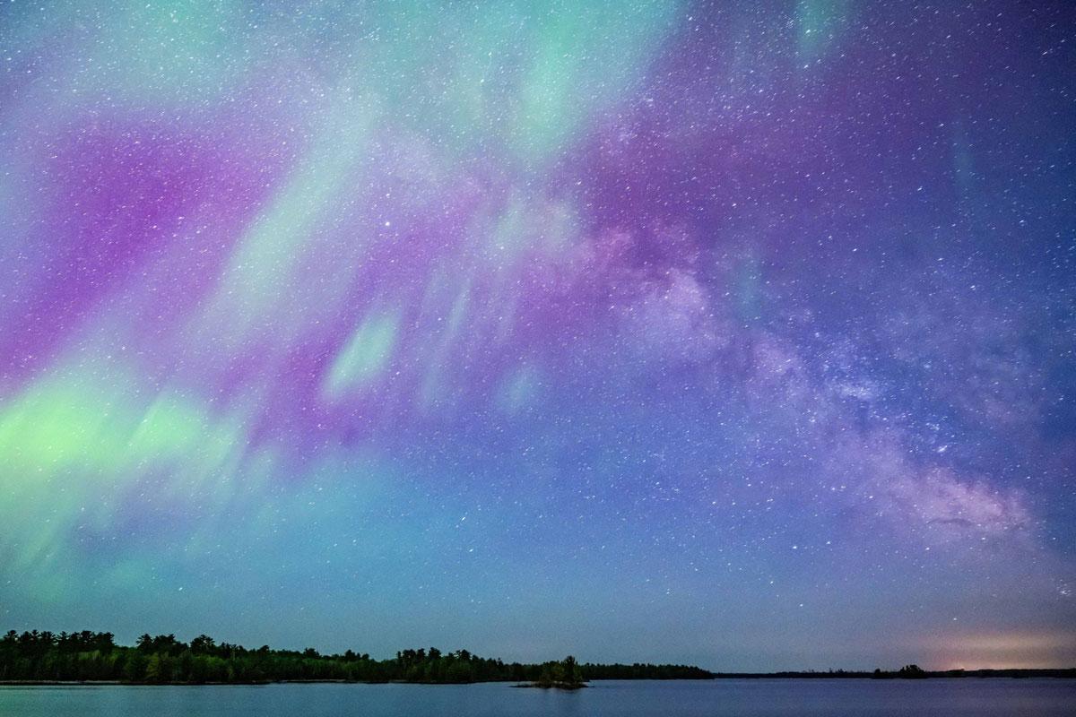 Photograph of Northern Lights and the Milky Way over a lake.
