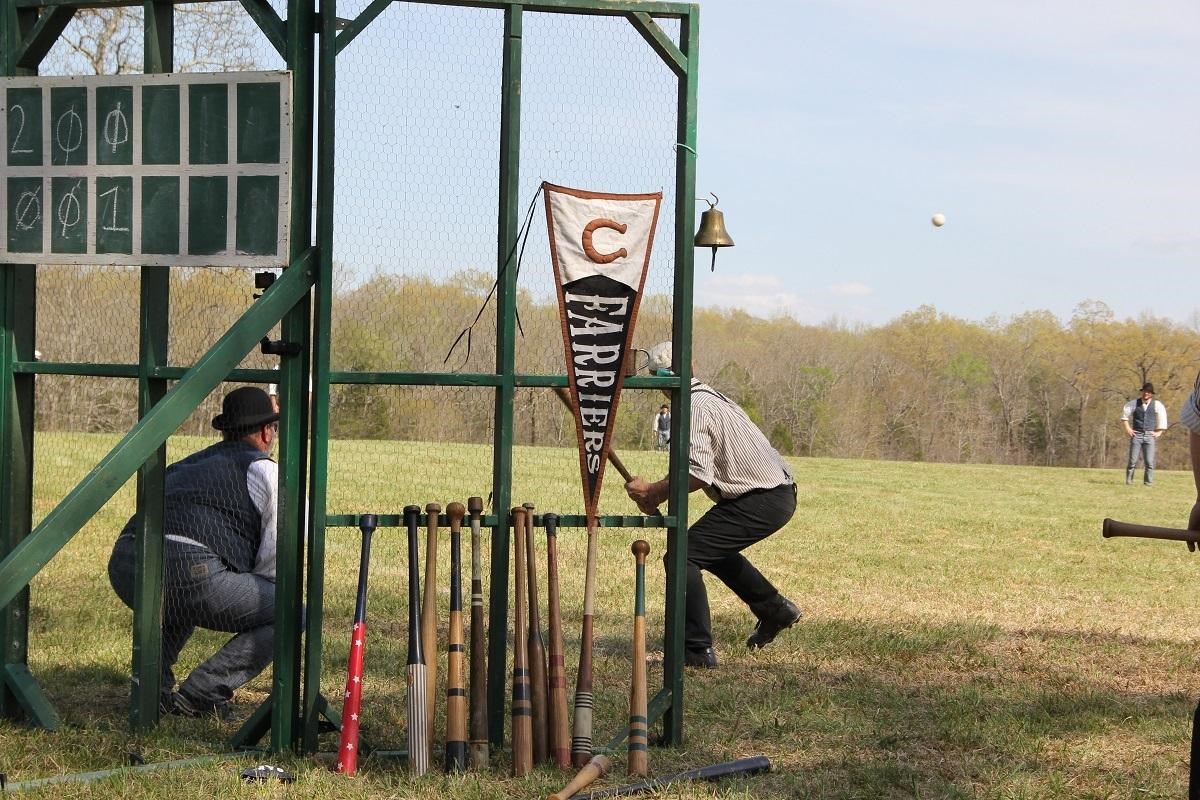 A baseball player in vintage unform prepares to swing at pitch